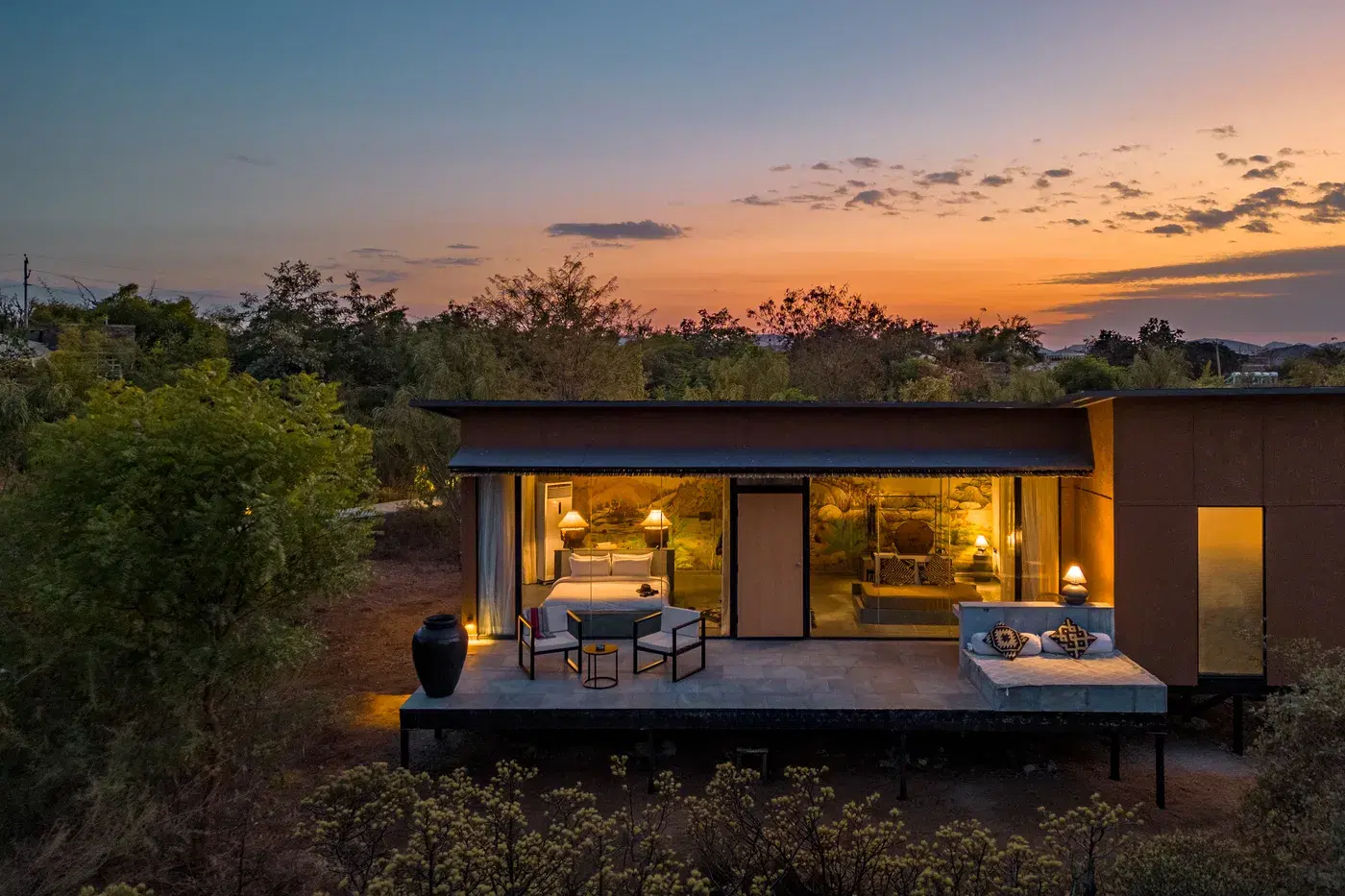 A boutique villa with its doors open onto a terrace at sunset